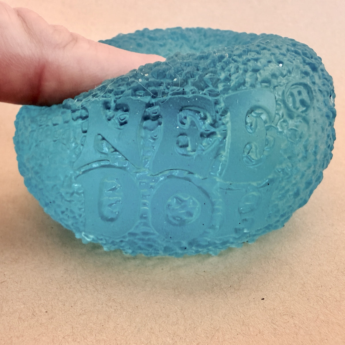 Hand squeezing a teal NeeDoh Gumdrop sensory squish toy